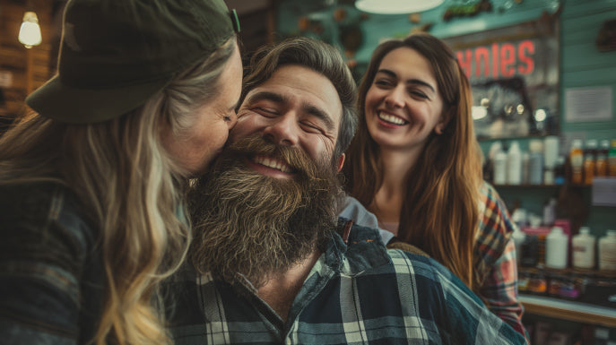 man with soft beard from beard oil having it smelled by his partner in barber shop