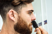 bearded man using milkman pocket comb on his moustache