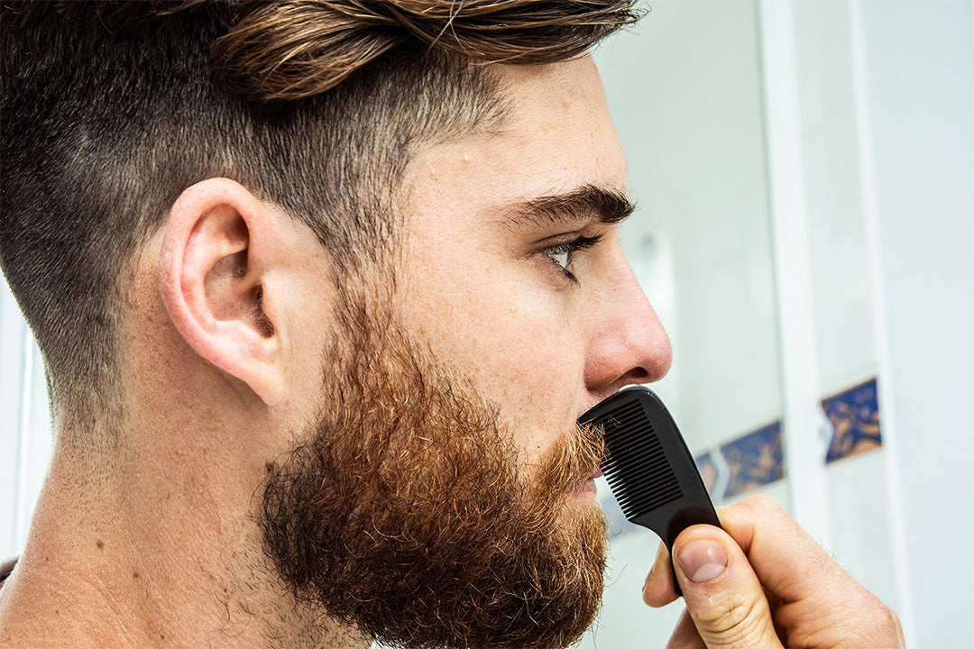 bearded man using milkman pocket comb on his moustache