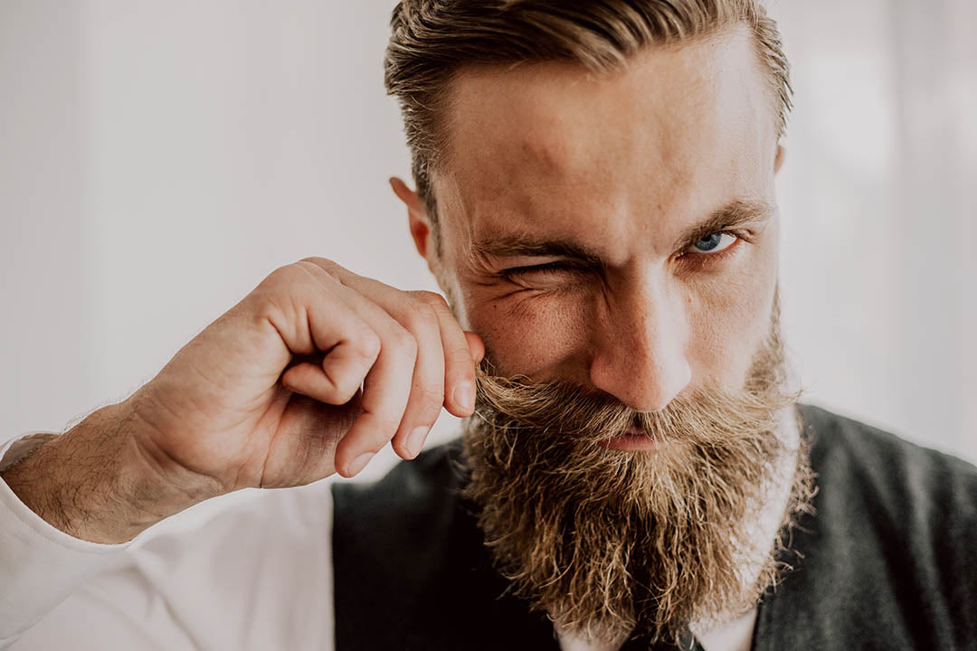 bearded man styling his beard with milkman beard balm